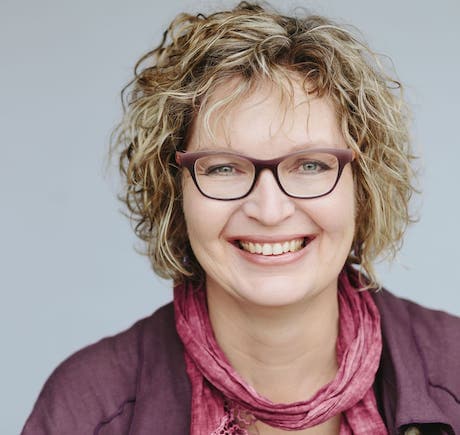 headshot of Candace Cox, showing her weathering a purple cardigan, pink scarf, glasses, and smiling at the camera.